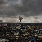 27 September 2018: A worker at Agbogbloshie carries material over an area which used to be a wetland.