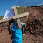 25 April 2019: A family member removes a pair of crosses that were placed at the site where eight bodies were uncovered after a mudslide behind the Westcliff Secondary School in Chatsworth, Durban, caused a house to collapse.