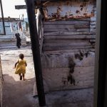 20 June 2019: Caleb Phula’s daughter plays outside his home in Siyanyanzela. Residue from a petrol bomb, potentially a politically motivated crime amid growing support for the Socialist Revolutionary Workers’ Party, can be seen on the wall in the foreground.