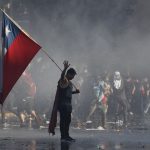 21 October 2019: A demonstrator in Santiago waving a Chilean flag during protests against President Sebastián Piñera, sparked by his announcement of a hike in peak subway fares. (Photograph by Marcelo Hernandez/Getty Images)