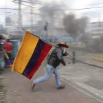 12 October 2019: A demonstrator running while holding an Ecuadorian flag in Quito, Ecuador, during a protest against President Lenín Moreno’s austerity measures. (Photographs by Reuters/Ivan Alvarado)