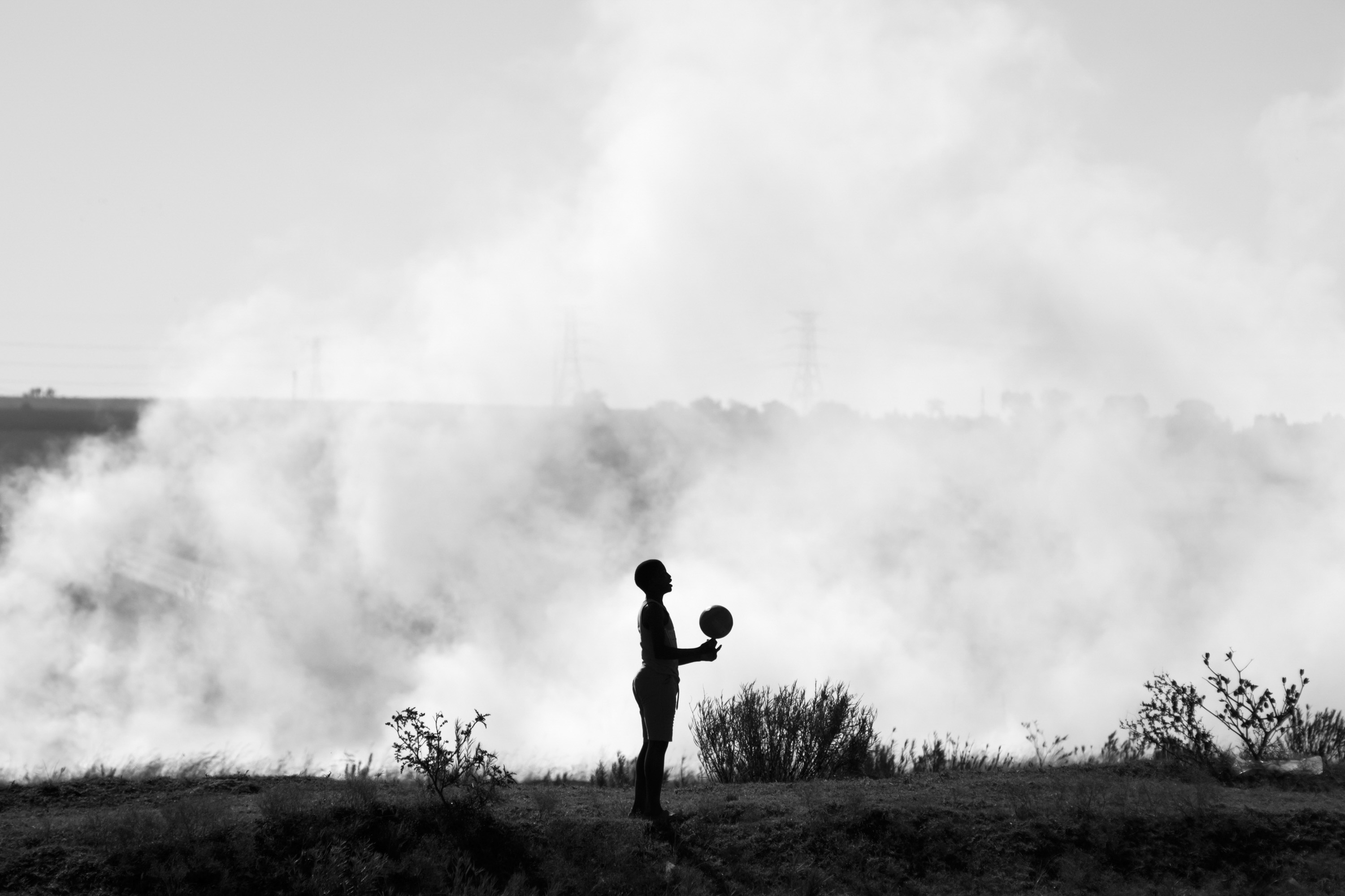 Child playing with ball near veld fire. Phola, Mpumalanga.