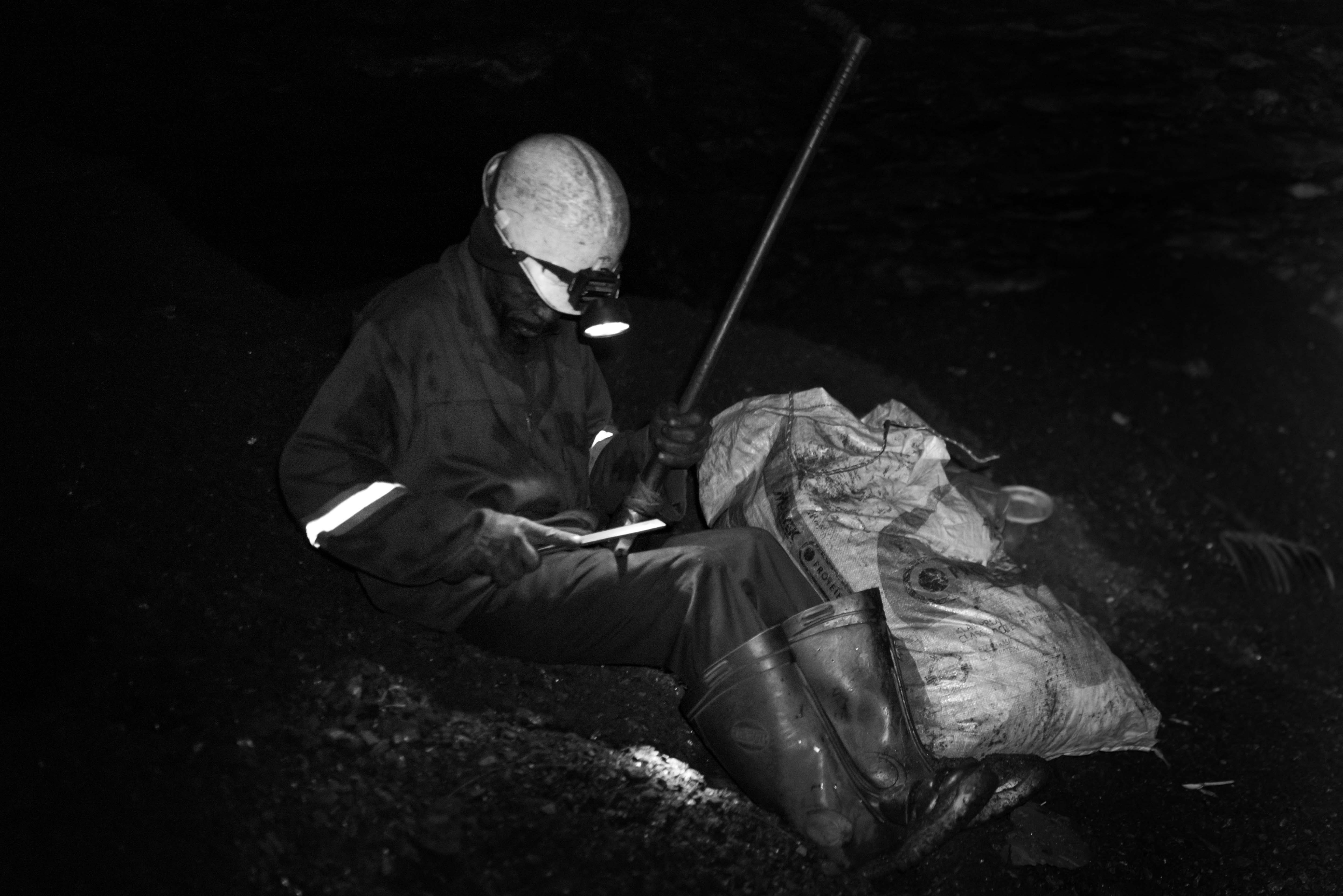 Unlicensed miner sharpening pickaxe. This miner, whose name has been withheld to protect his identity, has no formal training as a geologist. He has been using the skills he learned working for a mining company to mine independently since losing his job. Ermelo, Mpumalanga