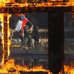 21 October 2019: A demonstrator waving a Chilean flag during a protest against President Sebastian Piñera’s subway fare hike in Santiago, Chile. Protests in a number of cities developed into looting and arson. (Photograph by Marcelo Hernandez/Getty Images)