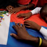 16 October 2019: A boy cries on the Haitian flag draping a coffin during a funeral for two men organised by the Popular and Democratic Sector in Port-au-Prince, Haiti. (Photograph by Reuters/Andres Martinez Casares)