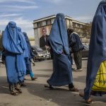 7 November 2019: Afghan women walk past a poster of President Hamid Karzai displayed on the side of the City Hall in Kabul, Afghanistan. (Photograph by Daniel Berehulak/Getty Images)