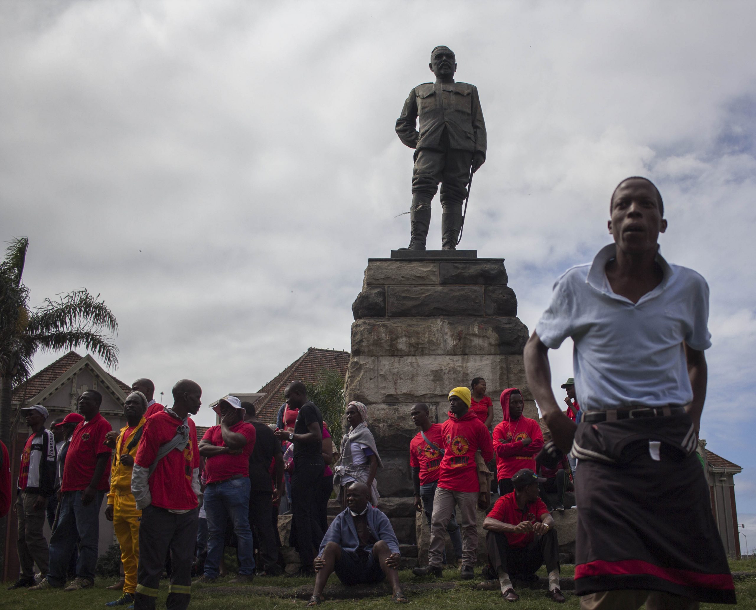 24 February 2020: A statue of Louis Botha, first prime minister of the Union of South Africa, towers over supporters of Abahlali baseMjondolo as they gather before the march.