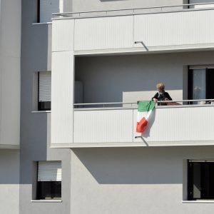 19 March 2020: A woman drapes the Italian flag from her balcony in Trento after the government took the unprecedented step of a nationwide lockdown, only allowing people to go to work or health centres. (Photograph by Alessio Coser/ Getty Images)