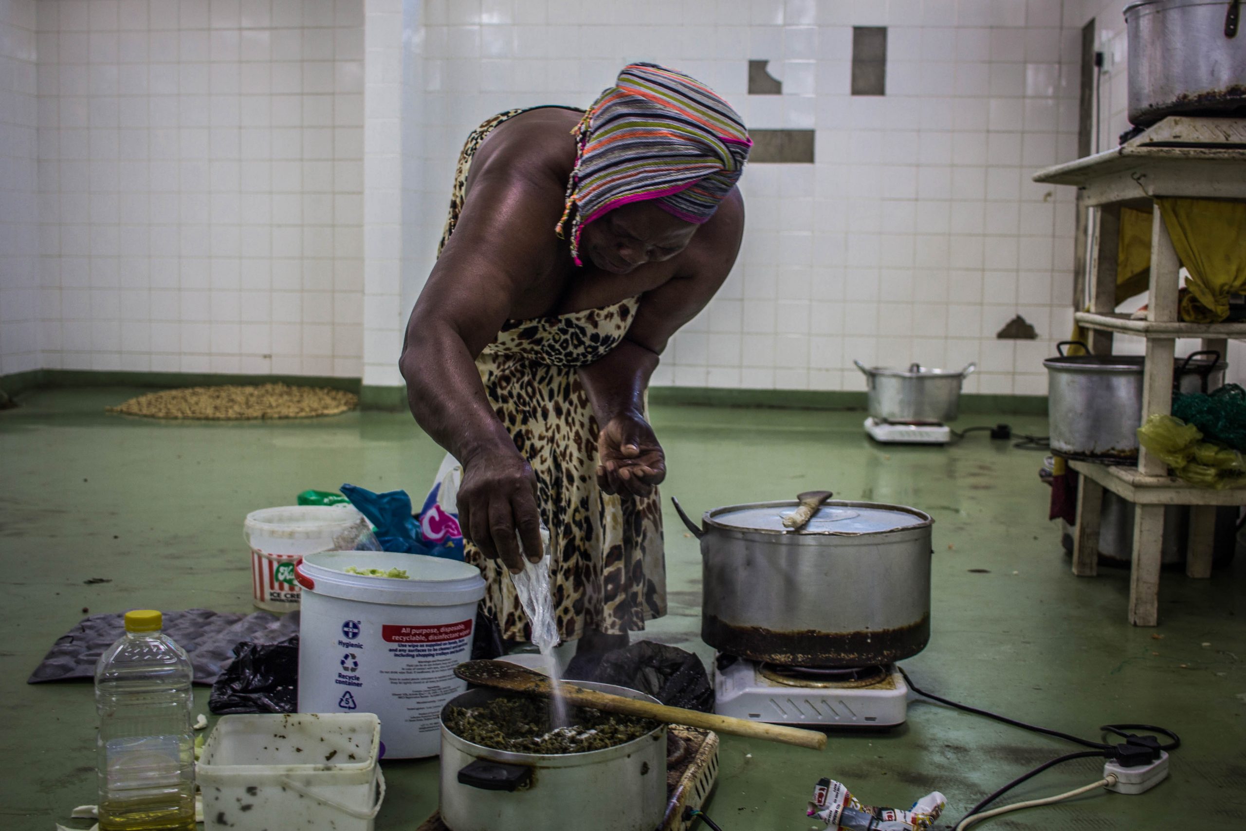 13 February 2020: Thandiwe Khathi adds salt to her food. One of the oldest women at the hostel, she wakes up at around 5am and begins to prepare food for her customers.