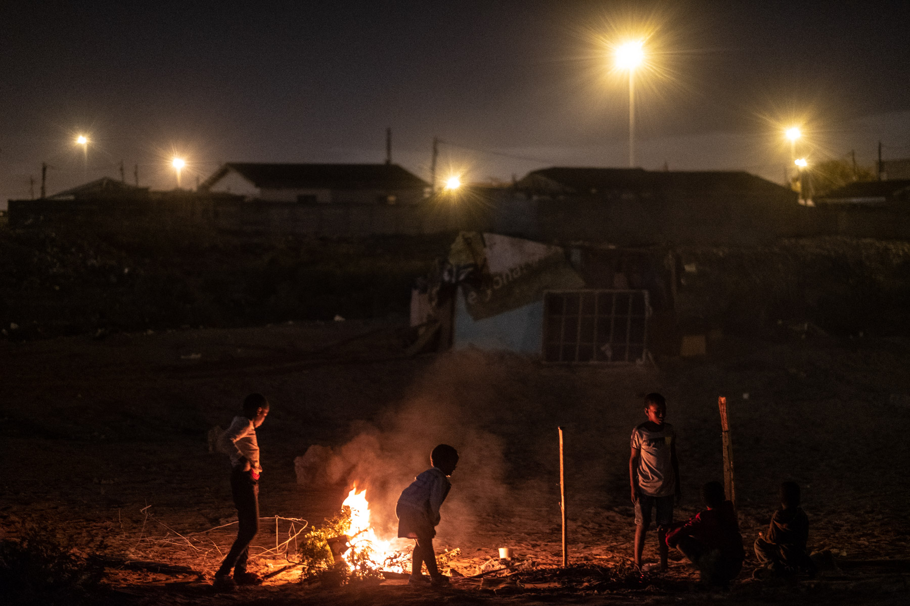 16 April 2020: Children who had been living in the demolished shacks play around a fire at night.