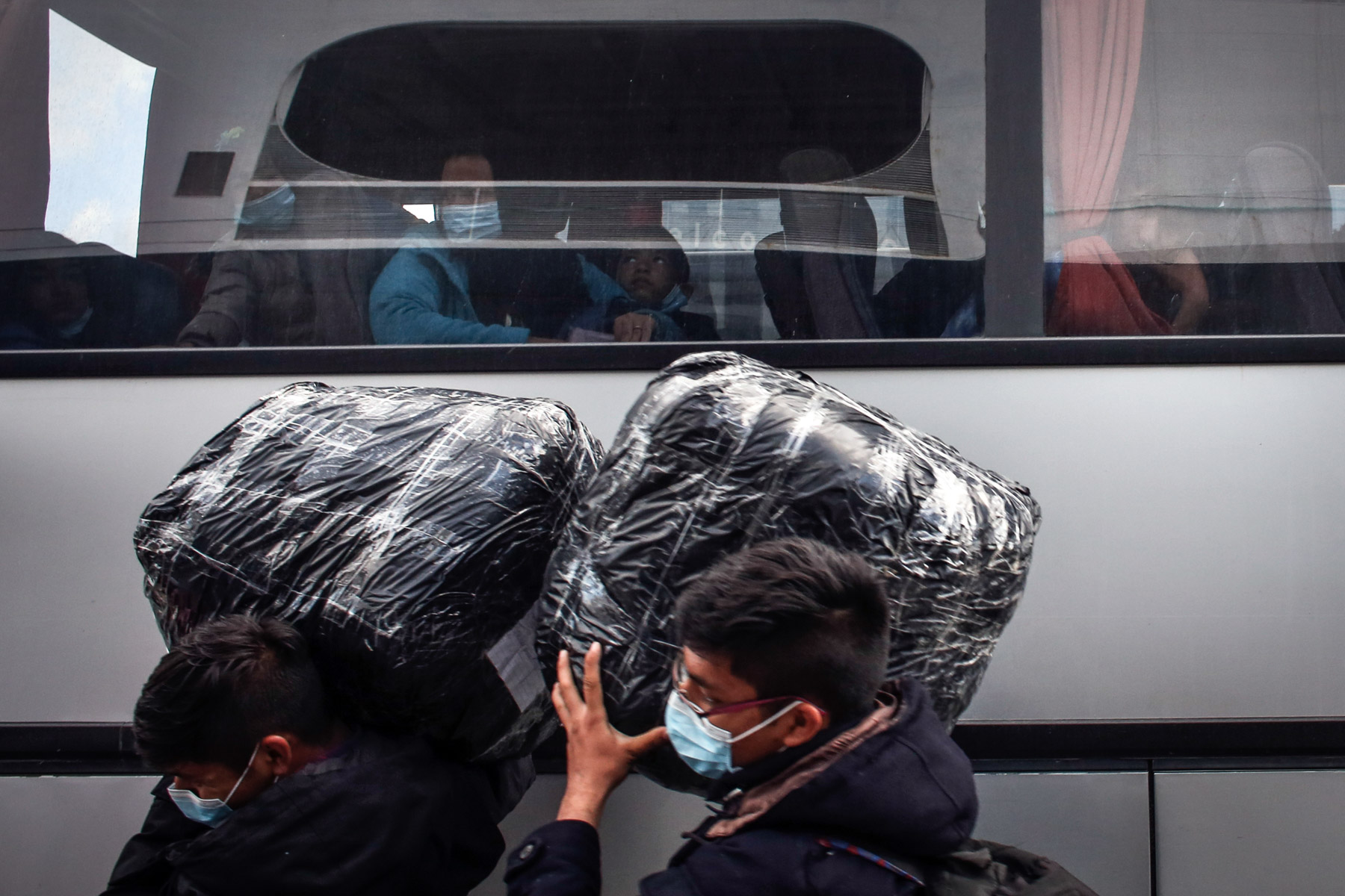 4 May 2020: Migrants wear masks as they wait for a bus at the port of Piraeus in Athens, Greece. The authorities moved 400 migrants to the mainland to ease overcrowding in the Moria camp on Lesbos island. (Photograph by Milos Bicanski/ Getty Images)