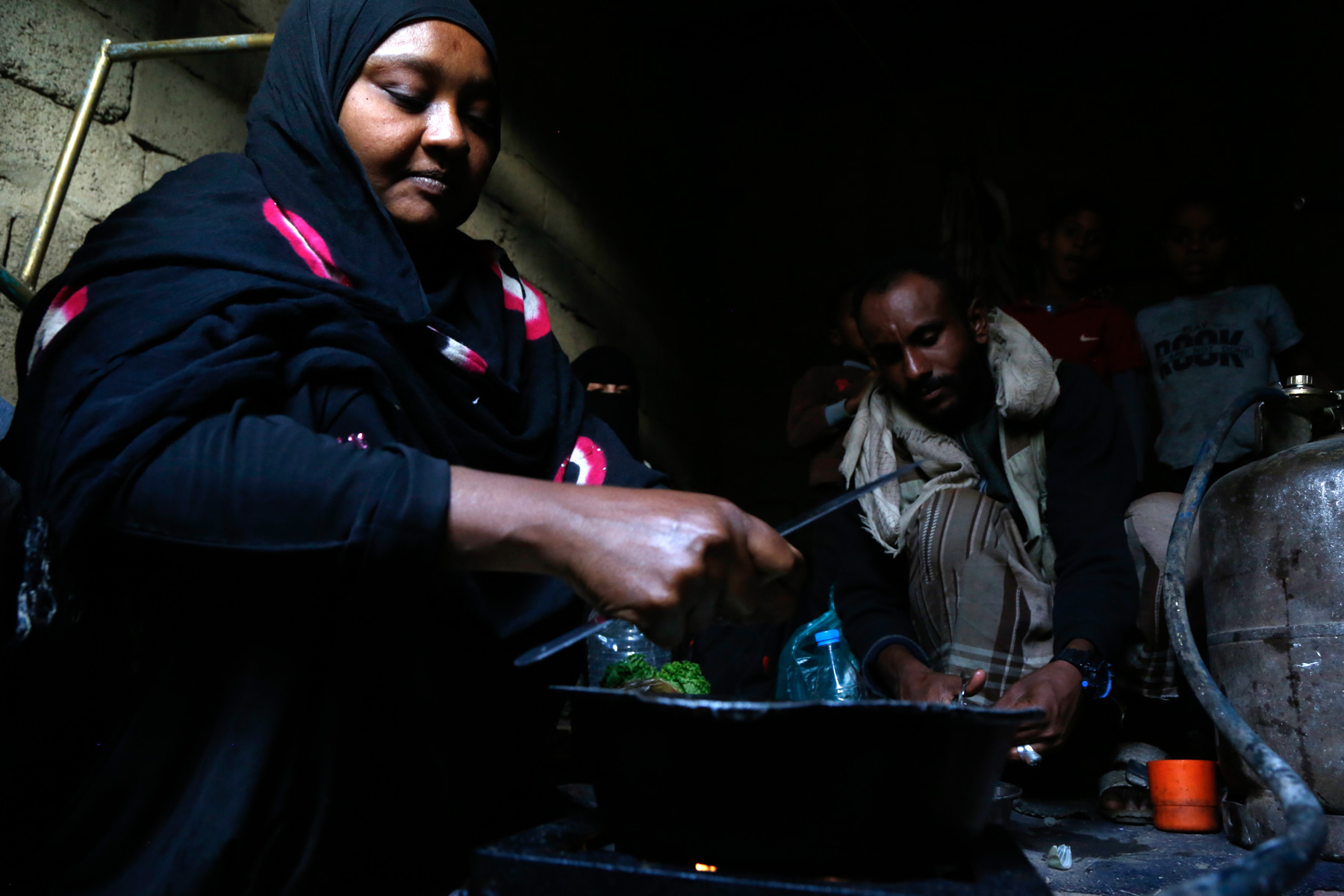 25 November 2019: Salwa Rajeh, a 45-year-old widow with four children, cooks in her rented shelter in Sana'a, Yemen. Intensifying fighting and airstrikes displaced her from Hodeida province three years earlier. ‘Most days we sleep hungry.’ (Photograph by Mohammed Hamoud/ Getty Images)