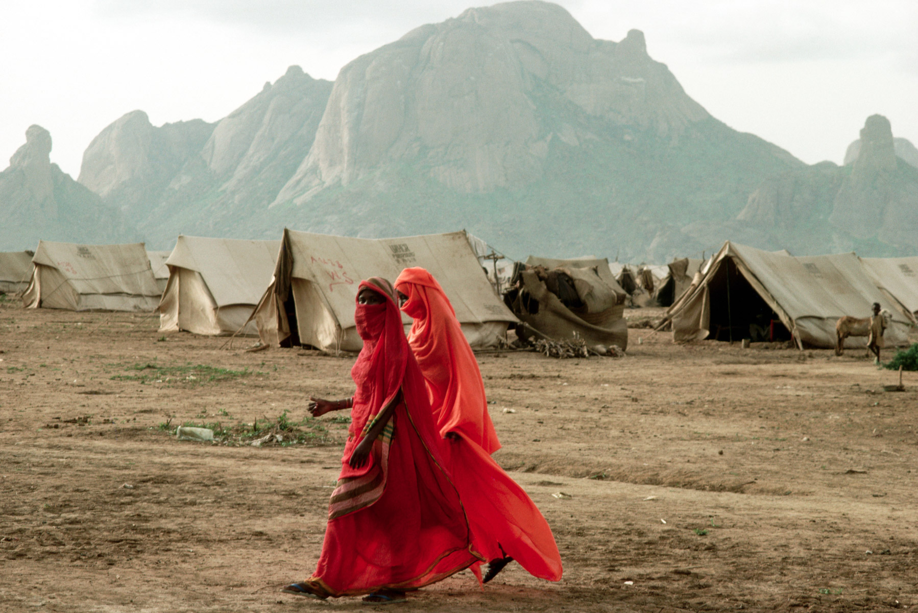 1988: Two women refugees from Eritrea, then still under annexation by Ethiopia, walk past a refugee camp in east Sudan dressed in traditional robes. (Photograph by Peter Turnley/ Corbis/ VCG via Getty Images)