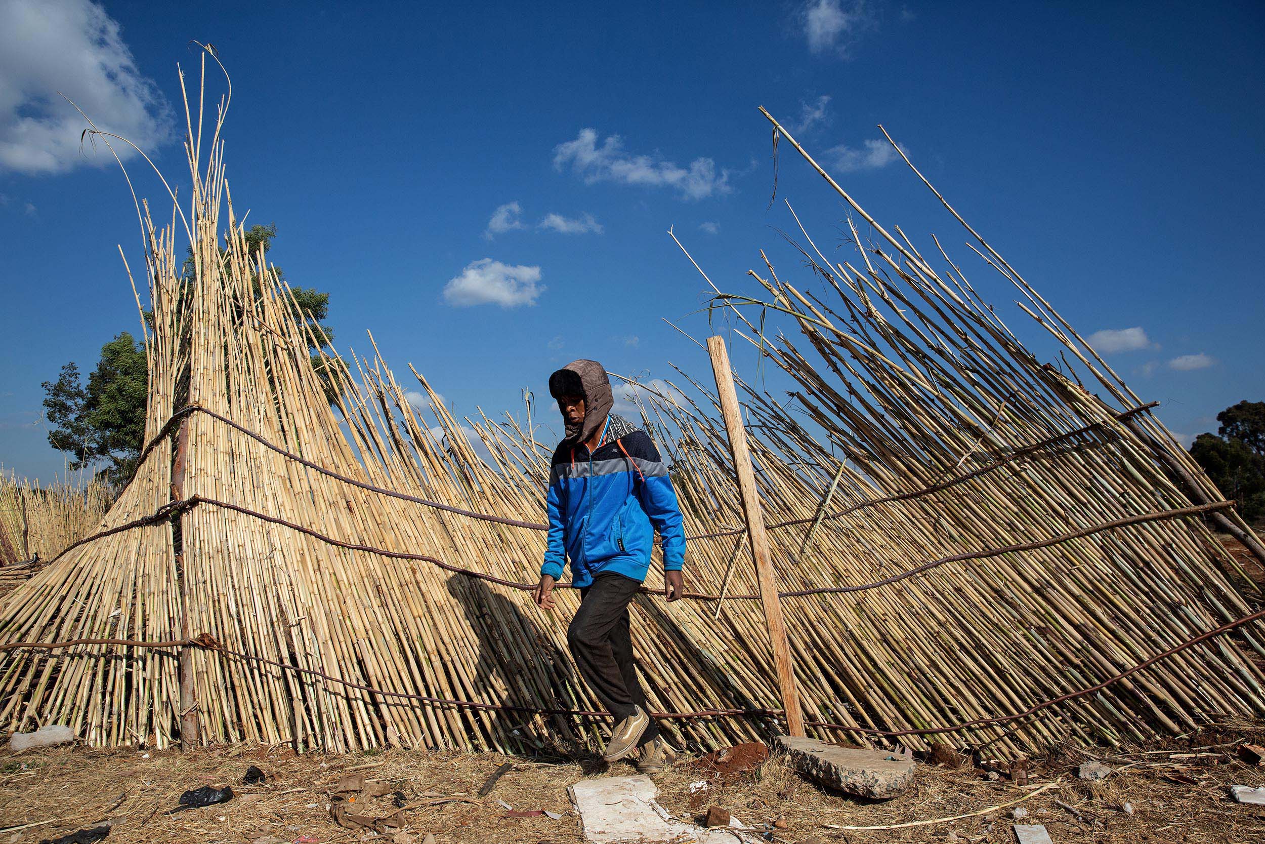 9 July 2020: A man fixes a fence blown down by the wind. The fence encloses a field that has been set aside to grow vegetables to assist the hungry Makause community.