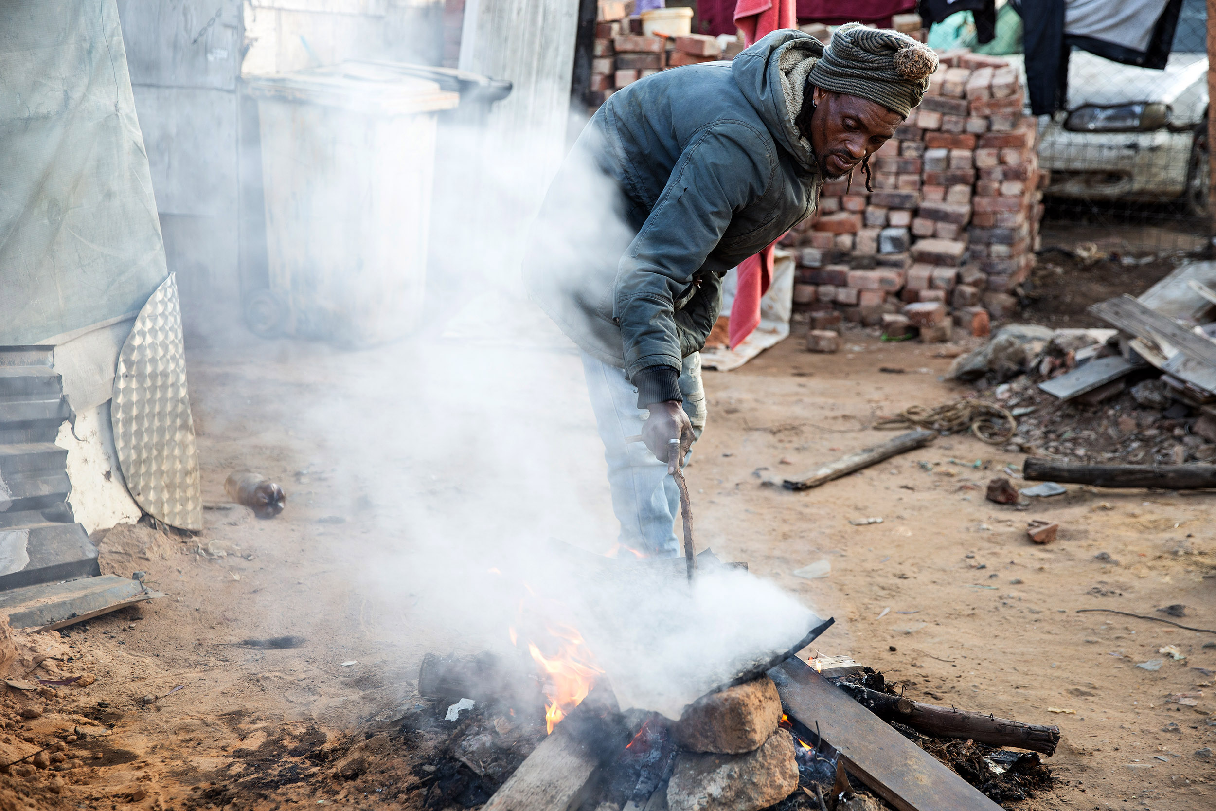  July 2020: Elliot Mokala processes some ore over a fire. Mokala, like many others, makes a living from artisanal mining in Makause shack settlement.