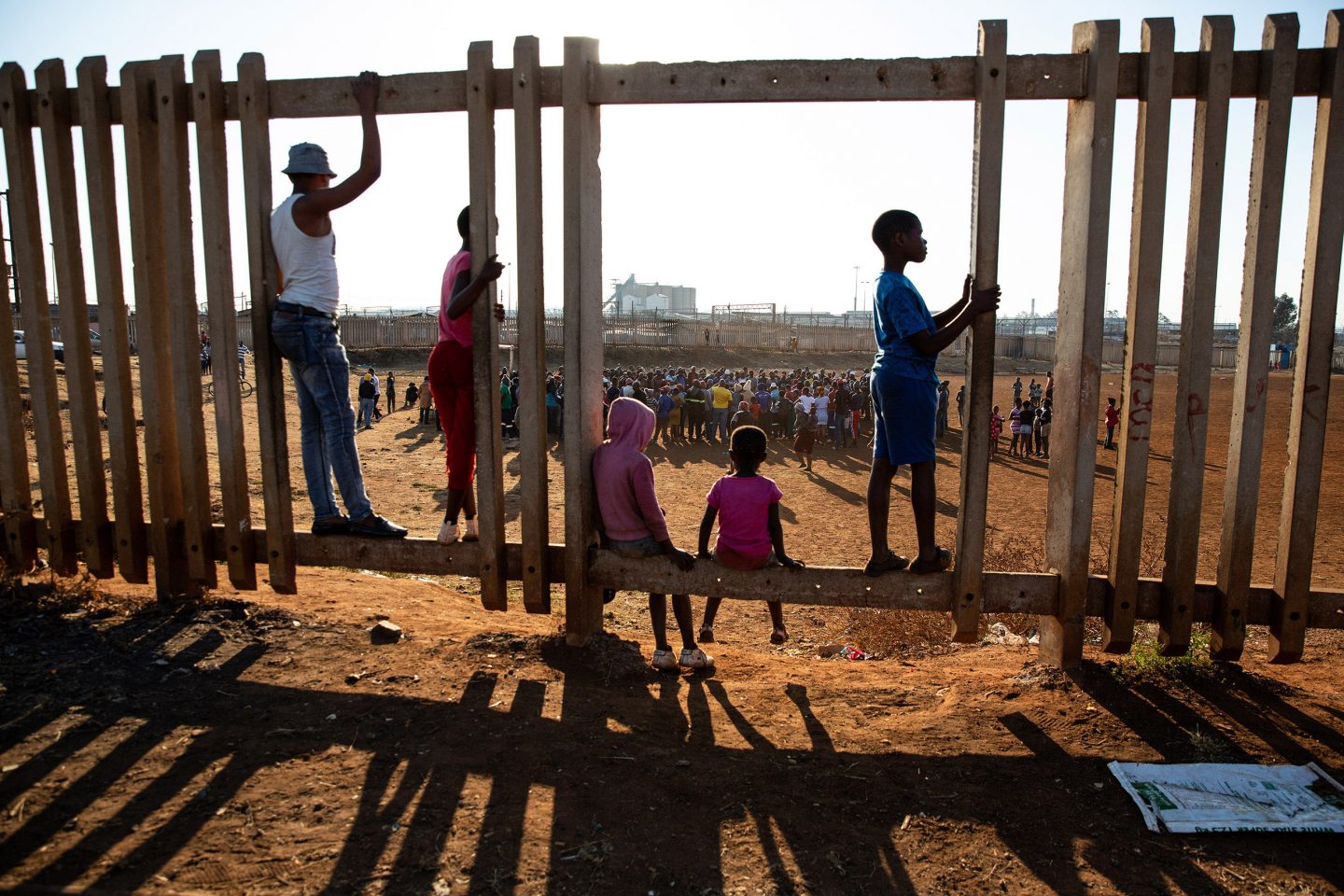 7 July 2020: Children watch the meeting taking place at a football field in Thokoza. A group of men marched in the township after taking part in the trucker’s strike. Xenophobic speech and threats towards migrants from other African countries characterised the protest. 