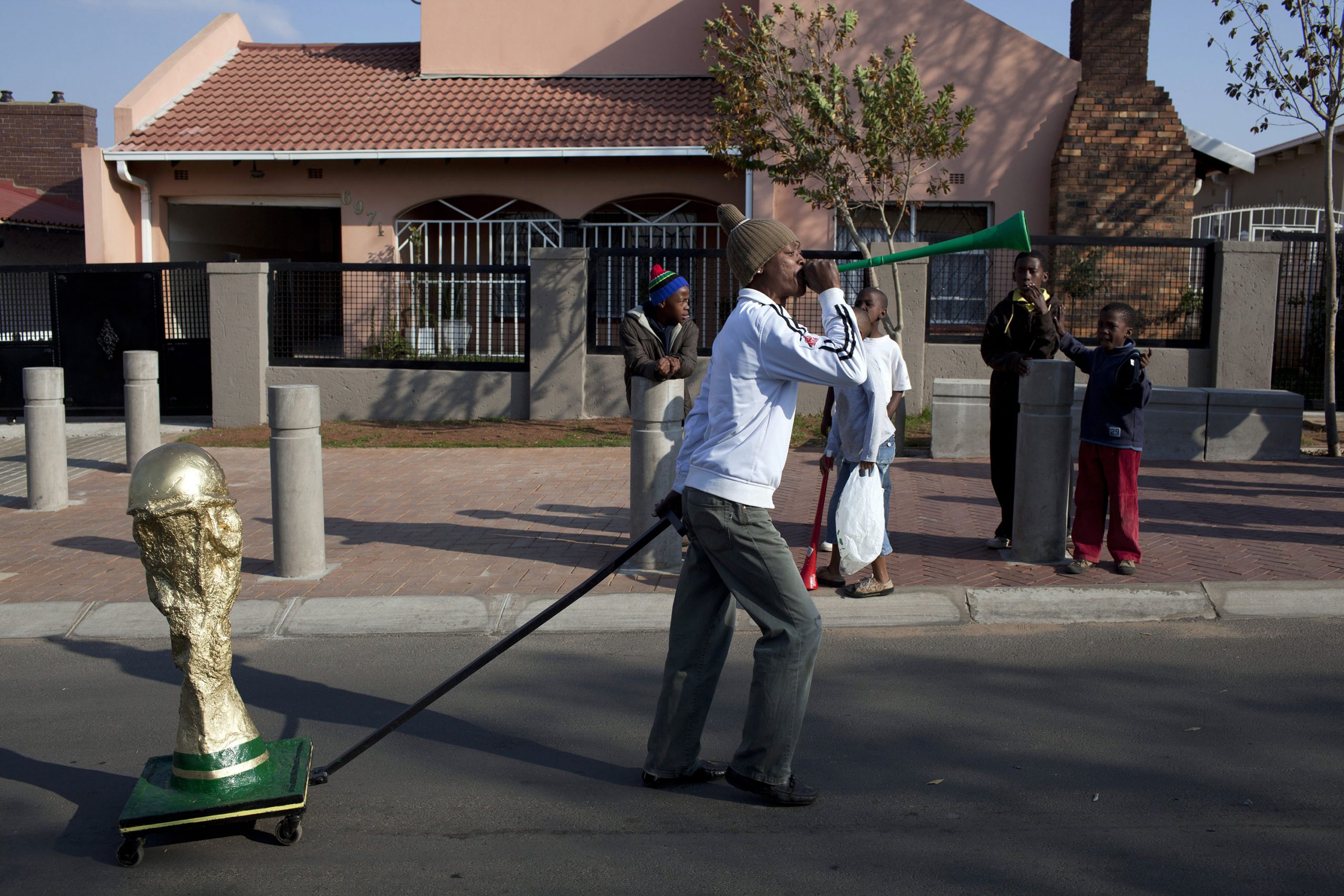 11 June 2010: A man pulls a cart with a homemade Fifa World Cup trophy on Vilakazi Street in Orlando, Soweto, as residents and visitors celebrate in the streets at the start of the tournament. (Photograph by Per-Anders Pettersson/ Getty Images)