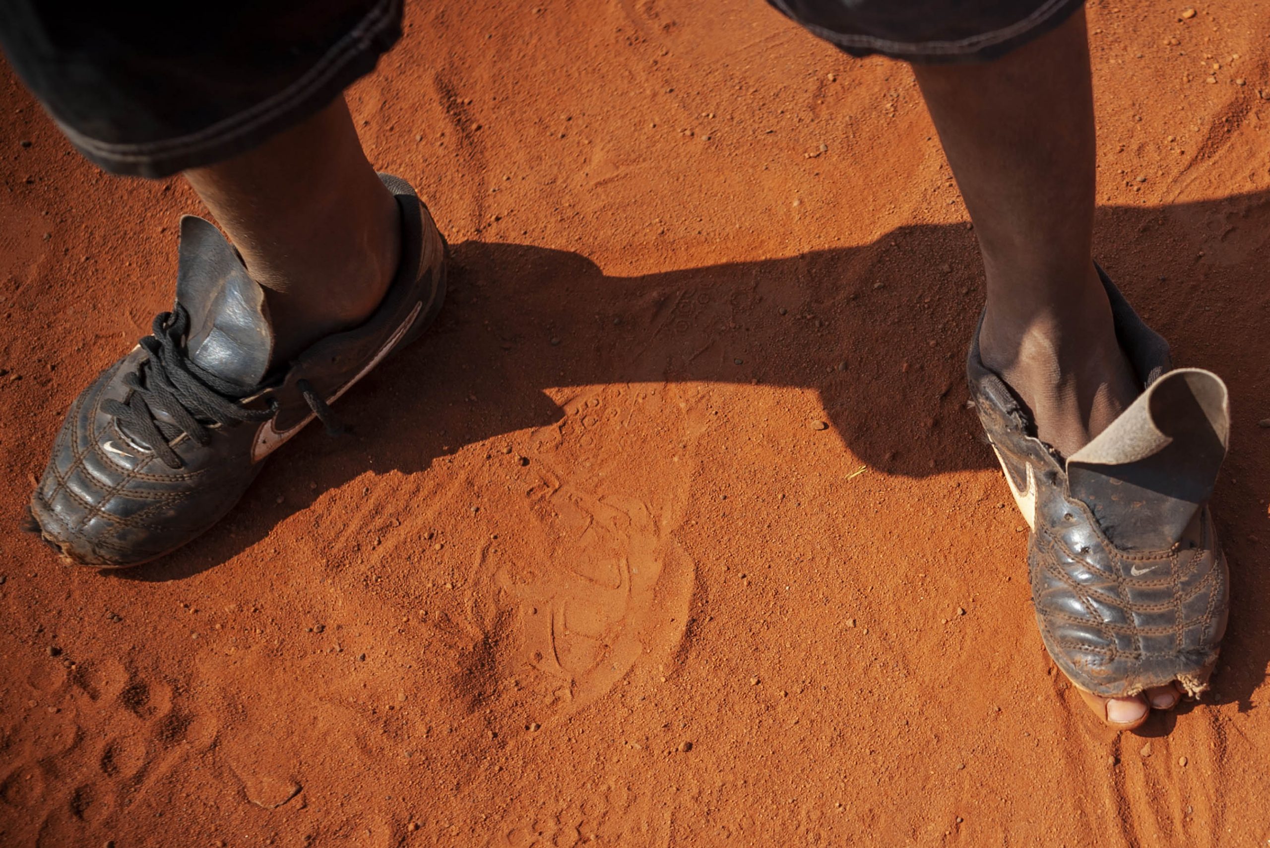 7 May 2014: A young Sowetan footballer’s toes peek out from his worn football boots as he takes a break during an informal game on a dusty football pitch in Dobsonville, Soweto. (Photograph by Ihsaan Haffejee) 